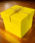 Yellow gift box with a bow tied with golden string on a wooden floor
