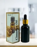 Cinnamon essential oil bottle with gold neck ring and brown paper box on light surface