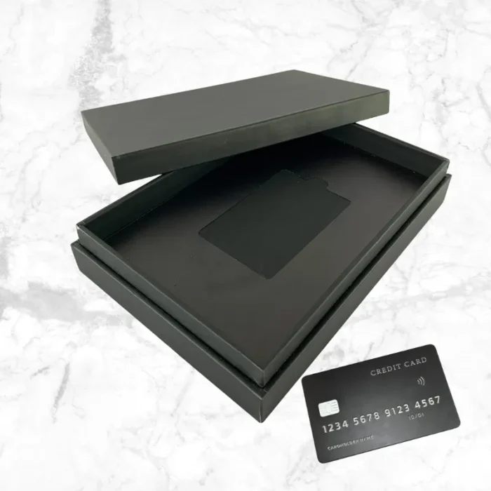 premium black card holder box matte finish with open lid showing credit card slot and black credit card on marble background