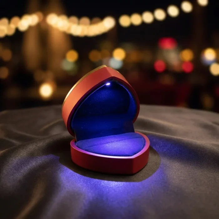 Premium red heart-shaped ring box with integrated LED spotlight illuminating an engagement ring on a velvet fabric background